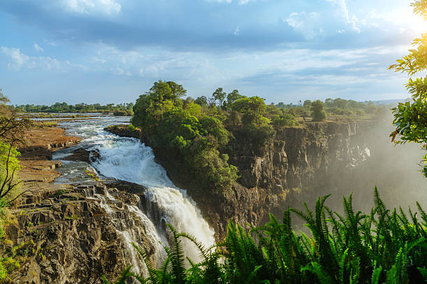 Zambesi River as it tumbles over Victoria Falls and Zambesi National Park. The Zambesi river forms a natural boundary between Zambia, Zimbabwe and Botswana where  wildlife can be found in the nature reserve and national park but most notable is the largest curtain of falling water in the world, Victoria Falls that has cut a deep zig-zag gorge through the underlying rock to create a dramatic scene known to tourists the world over