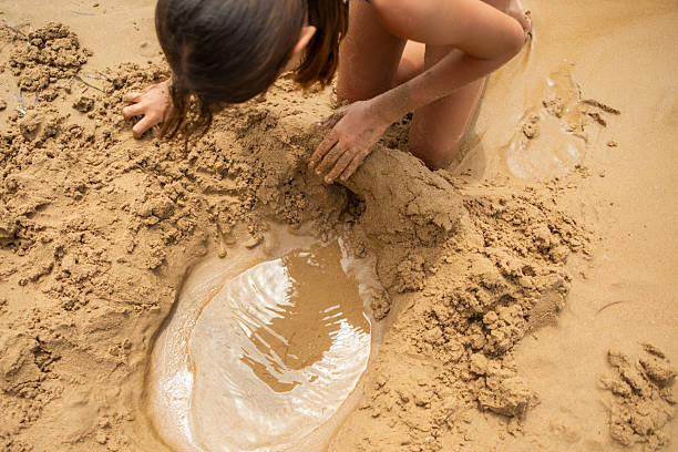 young girl playing with sand at the seashore