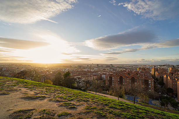 Majestic cityscape of madrid glowing under the setting sun, viewed from a hilltop park, showcasing urban beauty and natural serenity
