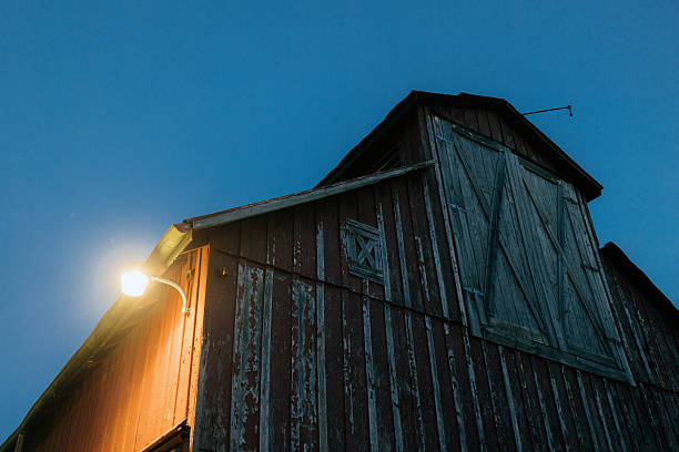 Rustic wooden barn beside rural road with dramatic sunset sky and colorful clouds in countryside
