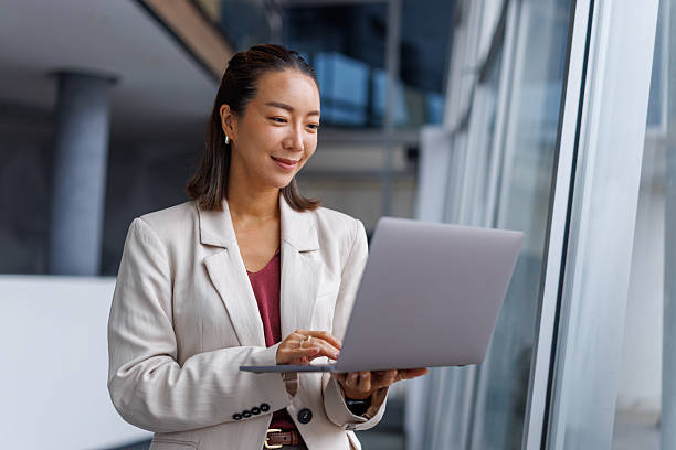 istock Asian businesswoman smiling while using laptop in modern office 2251418927