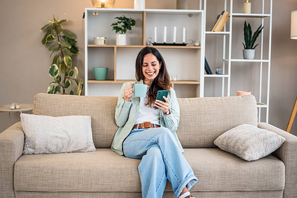 istock Happy woman relaxing on couch using smartphone 2251421295