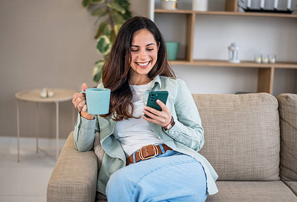 istock Woman relaxing at home using smartphone and drinking coffee 2251422089