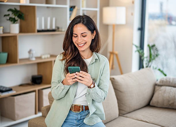 istock Woman smiling while messaging on smartphone at home 2251422171