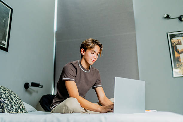 istock Teenage boy using laptop at home 2251422184