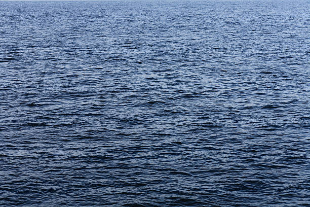 Serene Ocean Waves: Sunlit Water Ripples on Calm Blue Sea, Horizontal Close-Up Shot