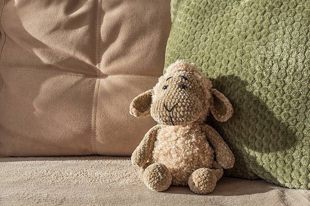 Knitted Plush Sheep on Beige Couch with Cushions in Natural Sun Light