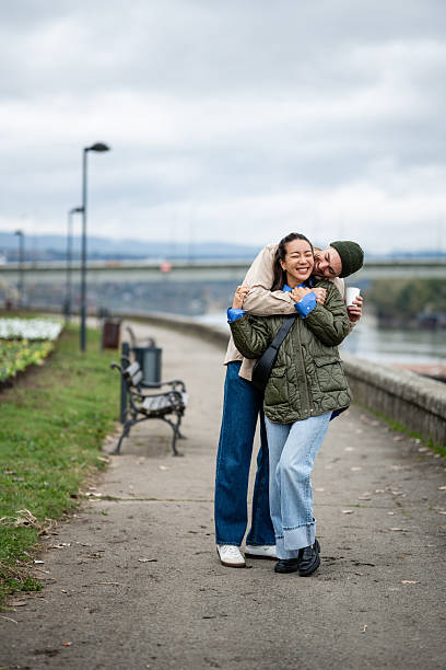 istock Loving couple hugging and walking along urban riverside park path 2251435597