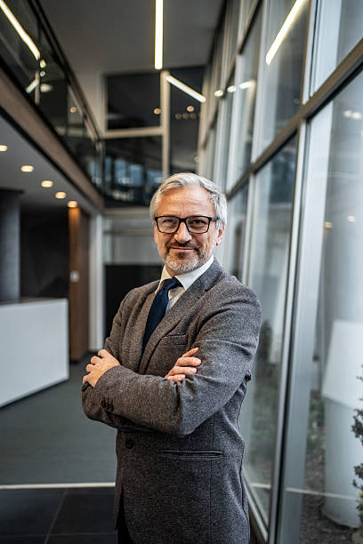 istock Mature businessman standing confidently with folded arms in modern office 2251439622