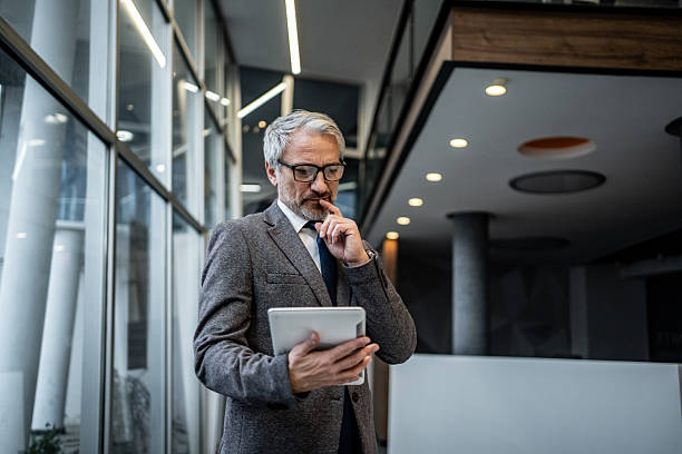 istock Mature businessman thinking deeply holding digital tablet 2251439679