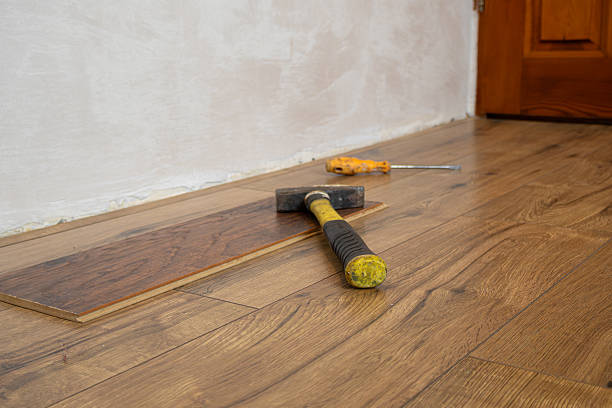 Tools are placed on newly installed laminate floor as work continues in a room, showing the process of home renovation.