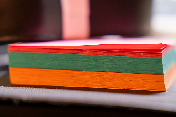 A vibrant stack of colorful sticky notes in red, green, and orange arranged on a work desk, showcasing a creative workspace ideal for note-taking and reminders.