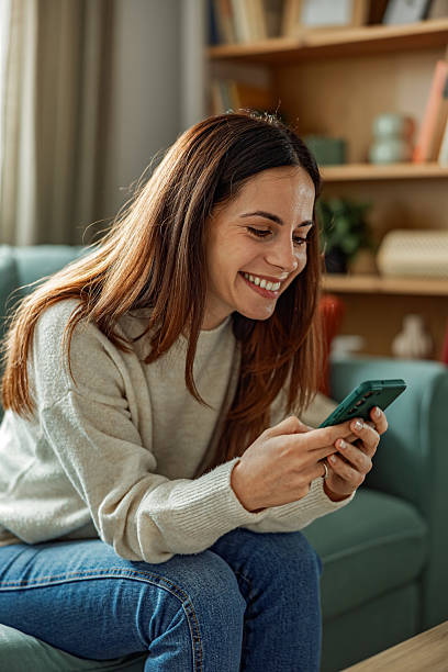 istock Happy Young Woman Smiling While Using Smartphone at Home 2251444019