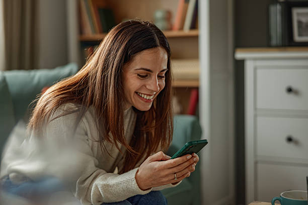 istock Happy Young Woman Smiling While Using Smartphone at Home 2251444047