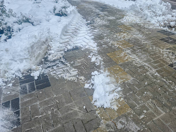 istock Snow-covered pavement shows traces of cleared paths surrounded by untouched white snow. Cold winter scene evokes the stillness and beauty of a snowy day. 2251444115