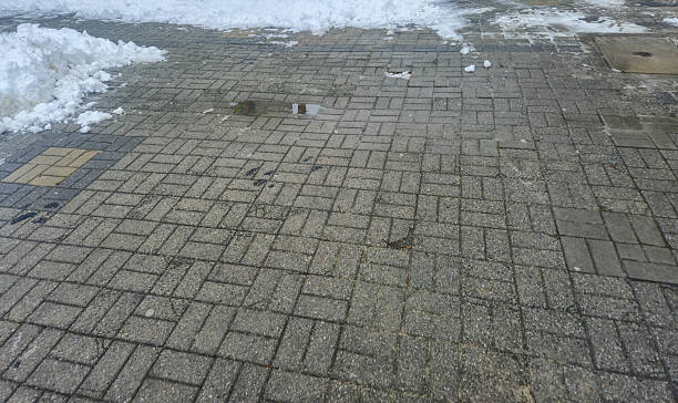 istock Wet cobblestone pavement with snow remnants on the side, reflecting winter elements. Ideal for showcasing urban winter conditions in city landscapes. 2251444174