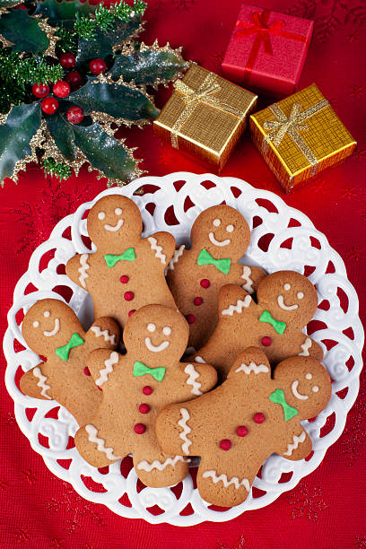 Gingerbread man with festive icing on white plate. Christmas cookie on white background. Happy New Year. Flat lay