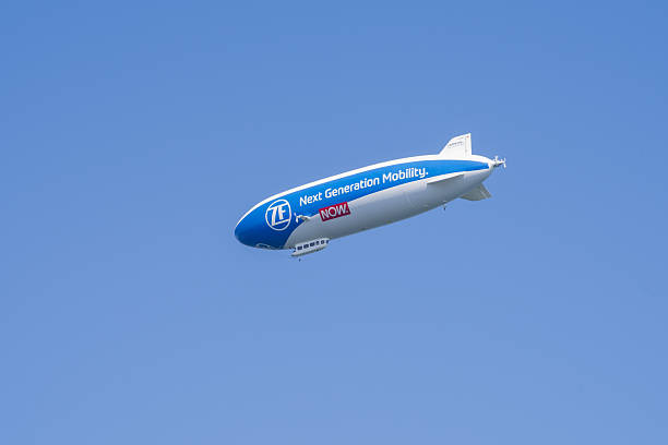 A modern Zeppelin airship featuring ZF’s branding glides gracefully across a cloudless blue sky. The clean aerodynamic shape and bright daylight emphasize the engineering and design of this contemporary aircraft. The minimal composition creates a striking visual focus on the airship itself, capturing a unique moment of calm and innovative aviation.