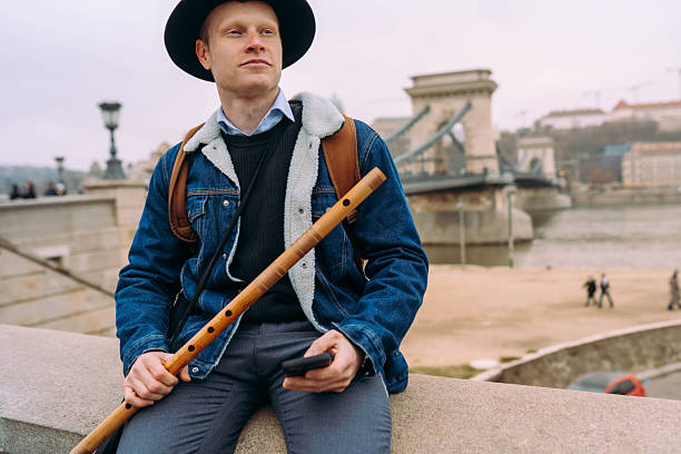 Handsome mail university student visiting Budapest and playing his instrument near the Chain Bridge