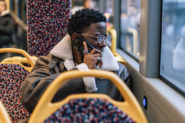 istock Dark-skinned African man sitting on public transport while talking on phone 2251460262