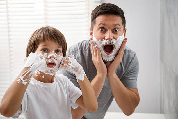 istock Father and son with shaving foam on their faces in bathroom 2251463773