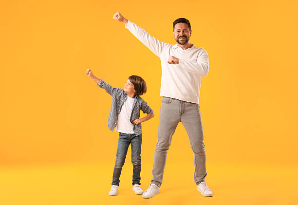 istock Father and son having fun on yellow background 2251464057