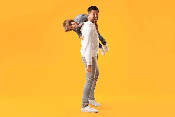 istock Father and son having fun on yellow background 2251464073