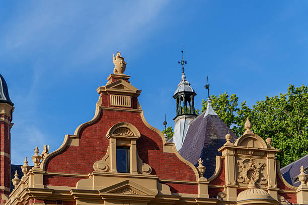 istock Elaborate Victorian-era Building Details Featuring Ornate Gables, Decorative Brickwork, a Unique Mythical Creature, and Weather Vane Under a Clear Blue Sky 2251466071