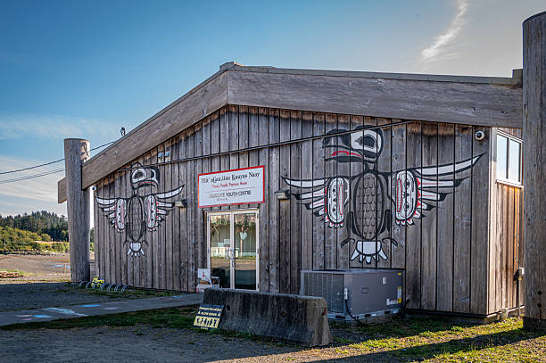 Skidegate, BC, Canada - Sept 7, 2025: An angled exterior view of the Hiit’agan.iina Kuuyas Naay, also known as the Young People’s Precious House youth centre on Front Street. The building features beautiful natural wood siding adorned with traditional Haida formline paintings of birds and spirit faces. This center serves as a cultural hub for the community, facilitating indigenous language learning, traditional arts, and youth engagement on Graham Island in Haida Gwaii.