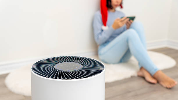 istock Air filter device in a cozy indoor setting, with a relaxed individual using a smartphone, showcasing modern Christmas home air purification technology 2251467591