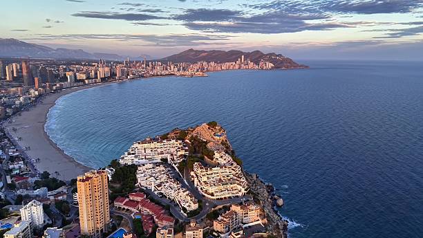 istock Spectacular cliffside scene during sunset featuring calm waters and sprawling city in background 2251470043