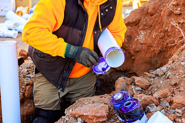 istock Worker installs pipes in trench at construction site while handling tools 2251471590