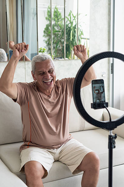 istock Senior man vlogging at home with ring light 2251473110