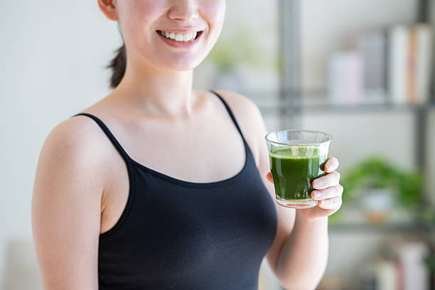 istock Young woman drinking green juice 2251473425