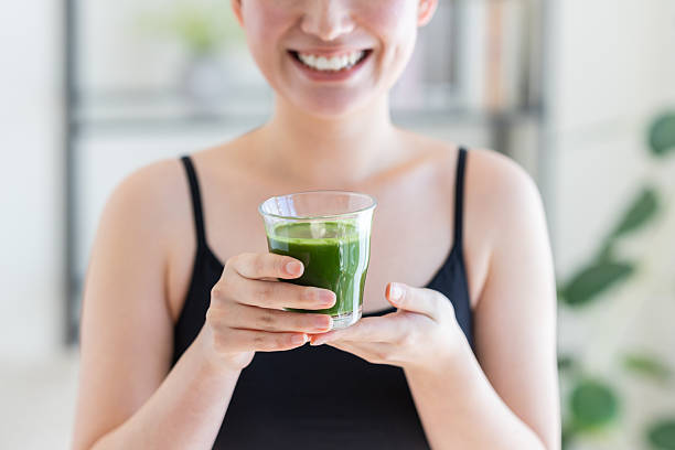 istock Young woman drinking green juice 2251473428