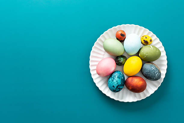 istock A beautiful assortment of Easter eggs in various colors and patterns is displayed on a round white plate against a bright blue background, perfect for holiday festivities 2251474678