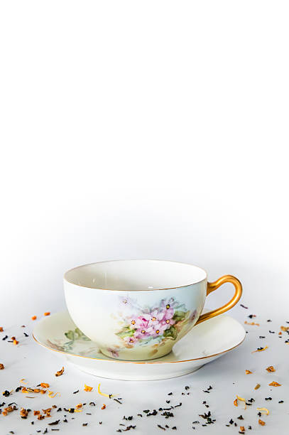 istock Empty teacup on saucer, tea leaves in foreground, white background, copy space above 2251474915