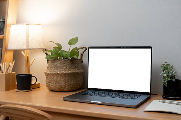 istock Cozy and warm home office setting with a laptop showing a blank white screen mockup, ambient lighting, and natural decor. 2251478357