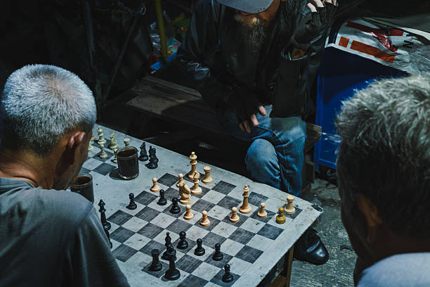 Balikpapan, Indonesia - November 1, 2025. Top-down view showing intense concentration during a serious street chess game between local men at night.