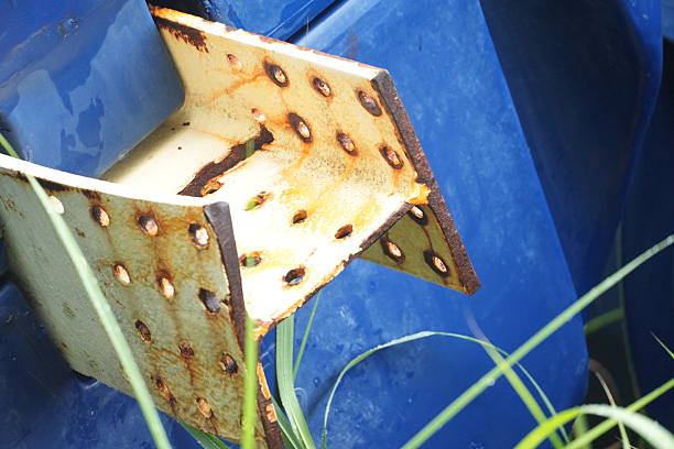 A rusty metal bracket on a blue background with green grass, conveying neglect and decay