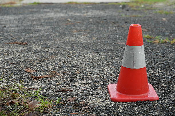 istock Vibrant orange traffic cone on cracked asphalt road surface 2251482108