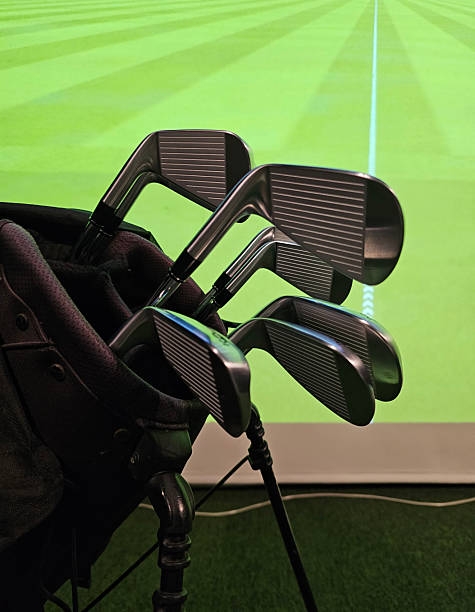 istock Golf clubs in a bag next to a simulator screen showing a golf course 2251488533