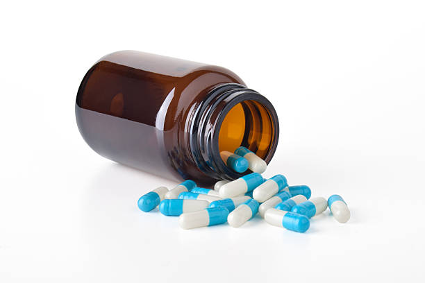 istock Antibiotic capsules spilling from a bottle on a white background 2251494121