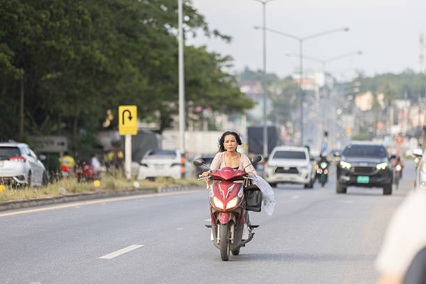 11 December 2025, Phuket Island - Thailand.Motorbikes are the most practical form of transport on Phuket iIsland, especially for short distances, errands, and commuting, and helmet use is often inconsistent despite safety regulations.