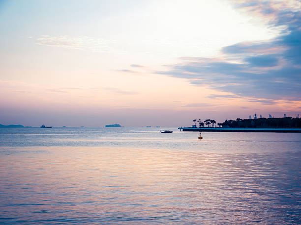 Shenzhen, China, a peninsula extending into the sea, bathed in orange sunset light reflecting on the water.