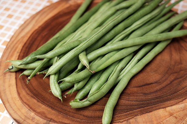 istock Freshly green beans arranged on a wooden cutting board create an appealing display against a table background 2251498281