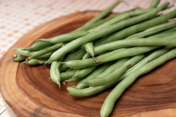 istock Freshly green beans arranged on a wooden cutting board create an appealing display against a table background 2251498427