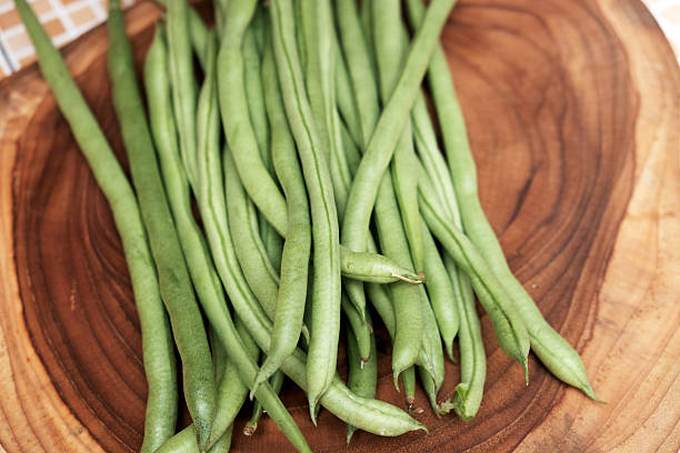 istock Freshly green beans arranged on a wooden cutting board create an appealing display against a table background 2251498511