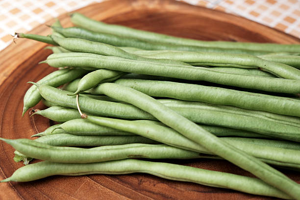 istock Freshly green beans arranged on a wooden cutting board create an appealing display against a table background 2251499358