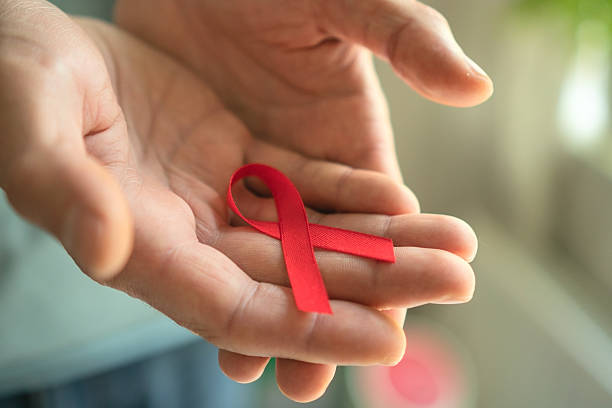 istock Mans Hands Presenting Red HIV AIDS Awareness Ribbon 2251499835